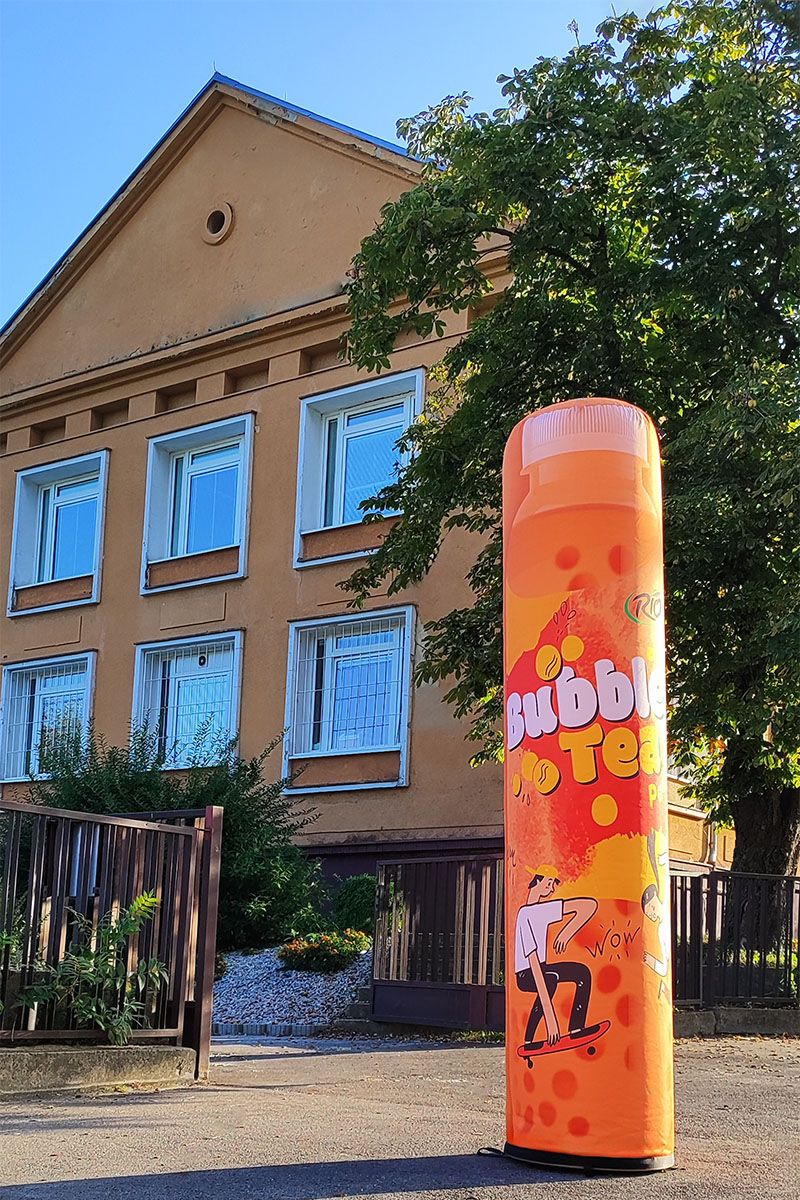 Reklamný stĺp oranžovej farby pri škole na Einsteinovej