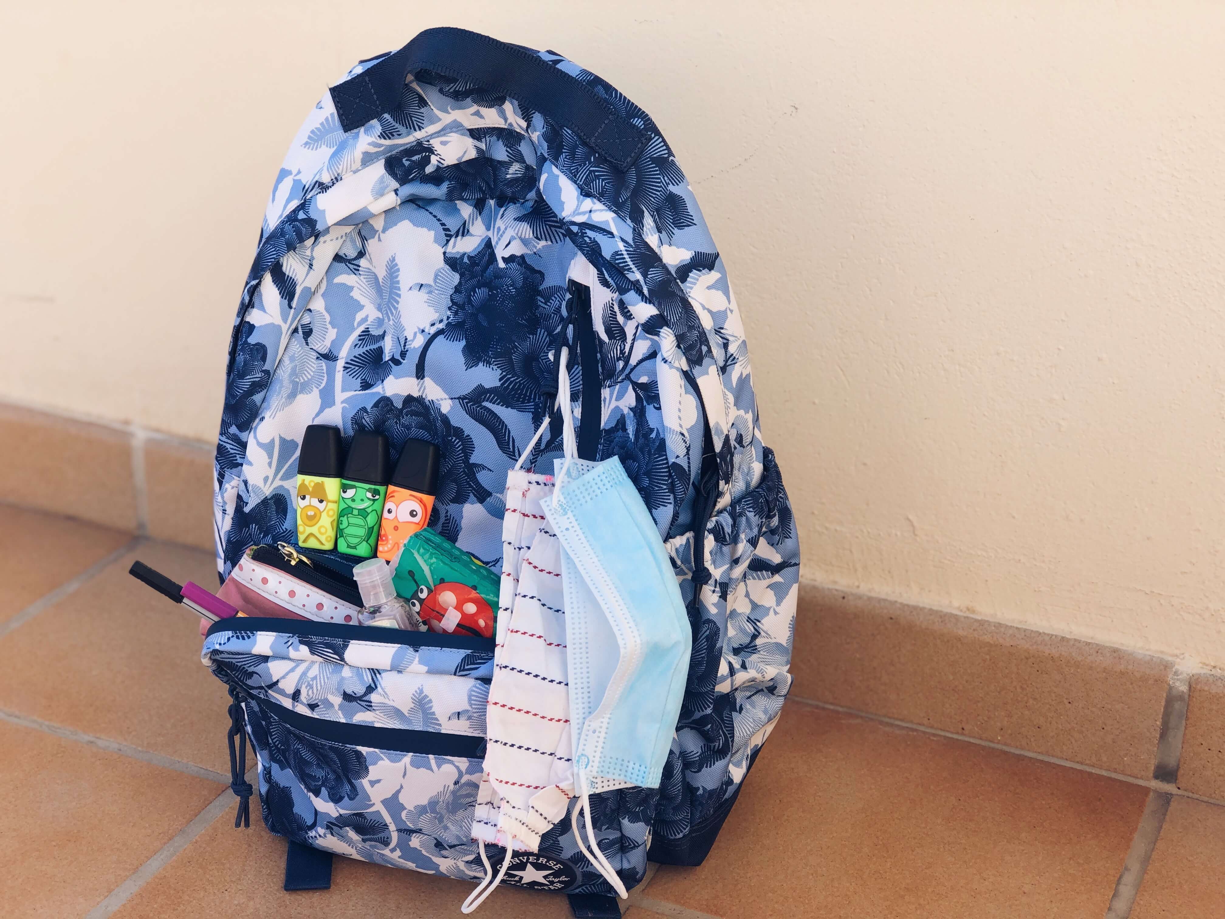 Rúška a písacie potreby pripravené na školskom batohu.