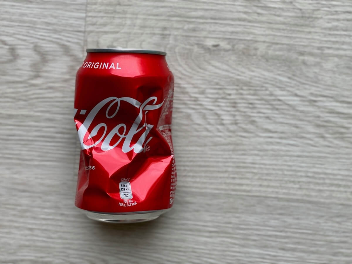 Pokrčená plechovka Coca Coly.