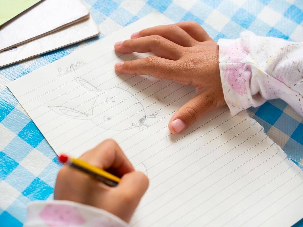 Dieťa kresliace obrázok zajaca ceruzkou v ľavej ruke.