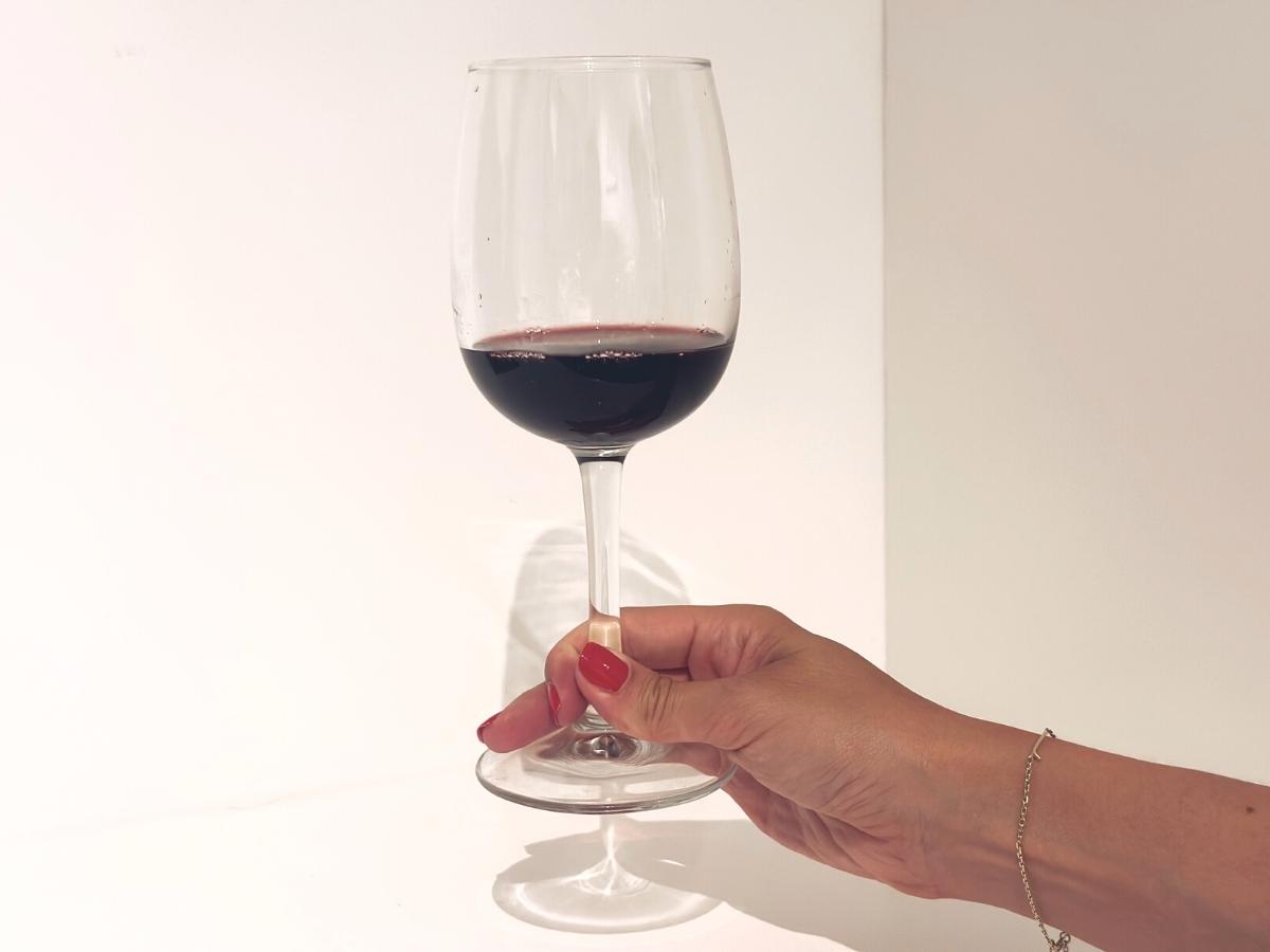 Držanie pohára s červeným vínom za stopku.