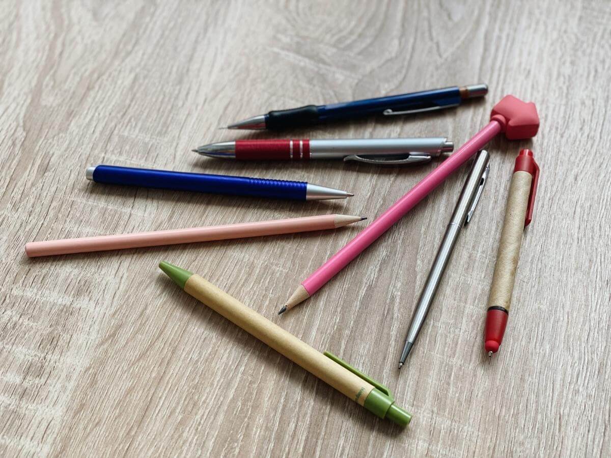 Rôzne perá a ceruzky položené na zemi.
