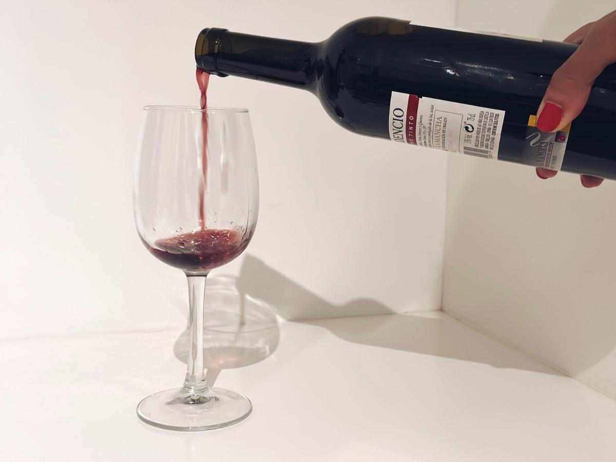 Nalievanie červeného vína do pohára.