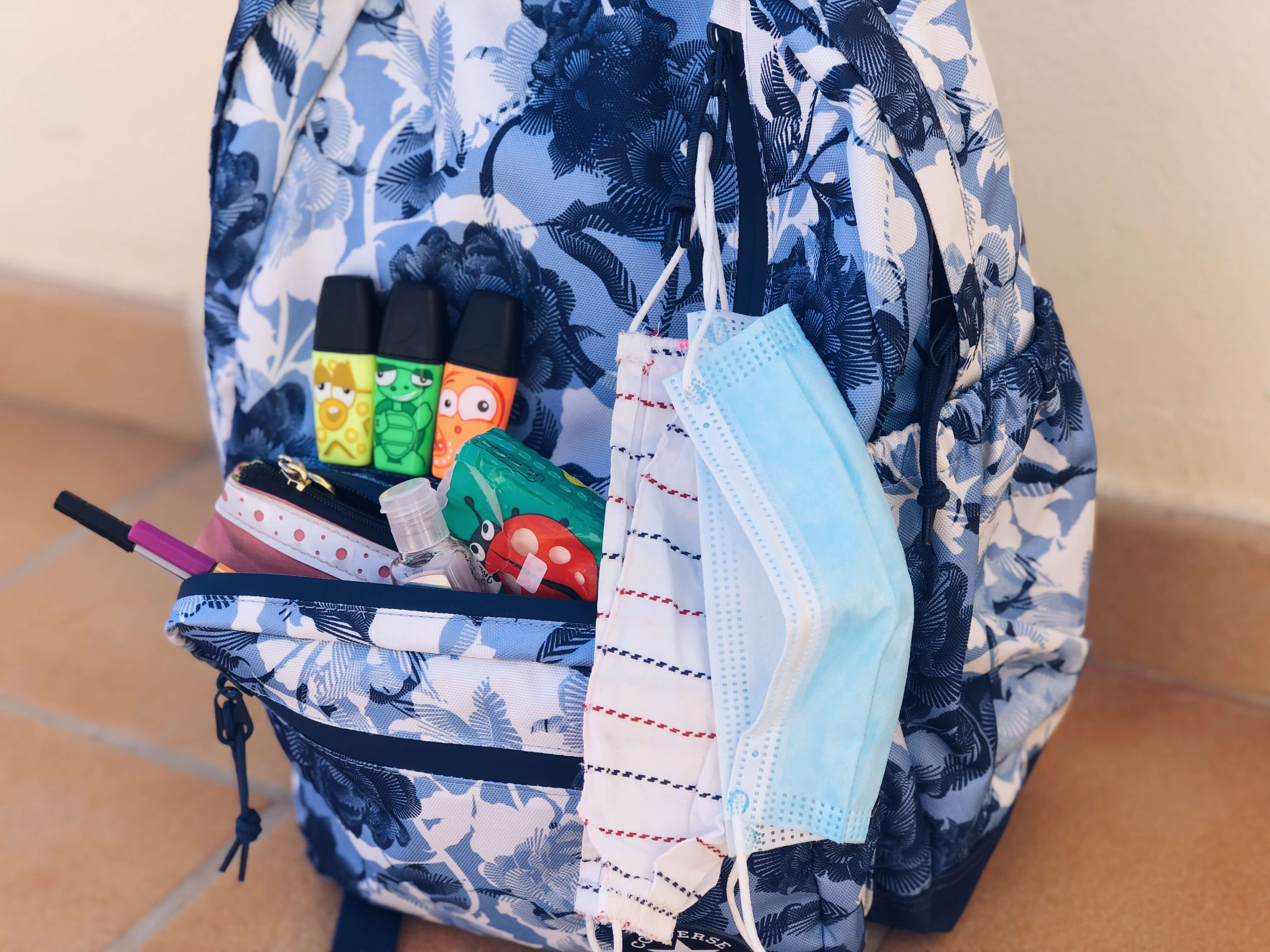 Rúška, antibakteriálny gél a písacie potreby pripravené na školskom batohu.