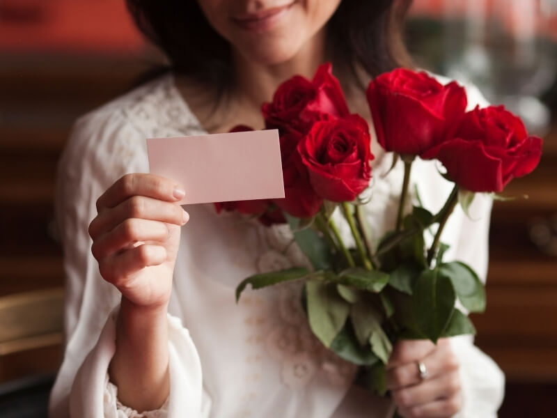 Žena s kyticou ruží a pohľadnicou na Valentína.