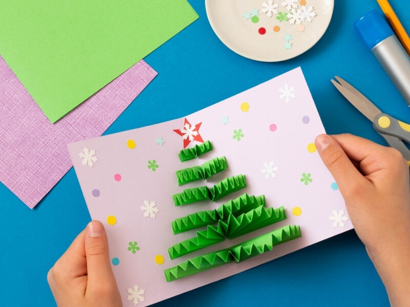 Vnútorná strana vianočnej pohľadnice s vyrobeným papierovým 3D vejárovitým stromčekom.