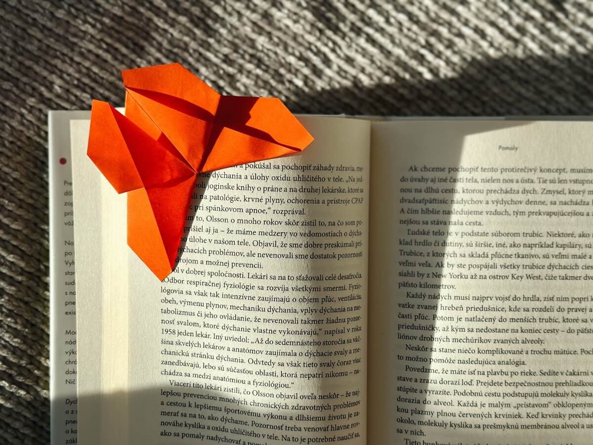 Oranžová záložka v tvare origami motýľa v knihe.